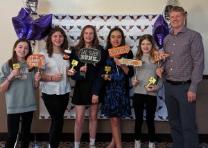 Photo of girls holding up trophies at banquet