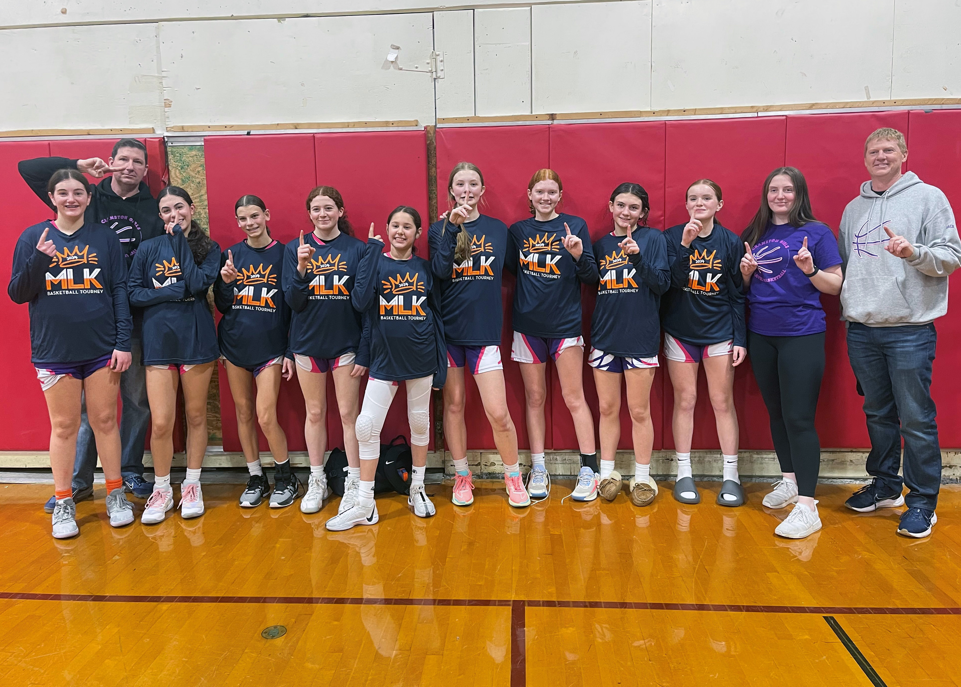 Photo of girls basketball team after winning championship holding up number 1