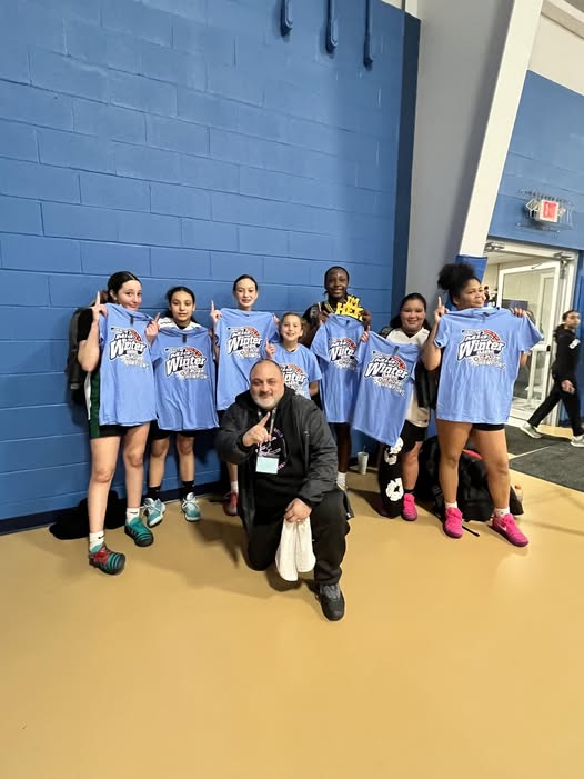 girls basketball team holding blue championship t shirts