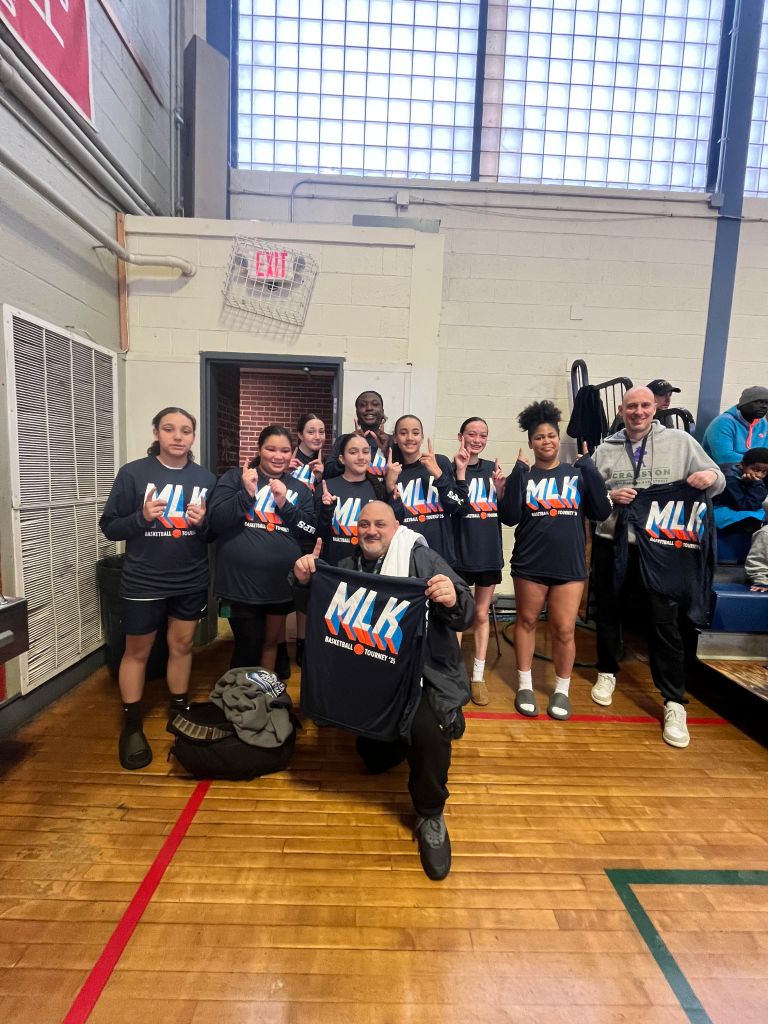 girls basketball team holding black championship t shirts